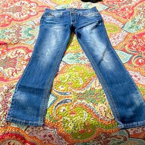 Medium wash denim jeans. With pocket embellishments with teal and pink threads.